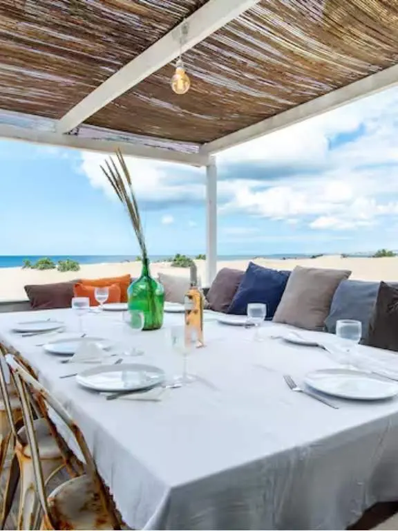 Beachfront dining terrace under a reed canopy with ocean views