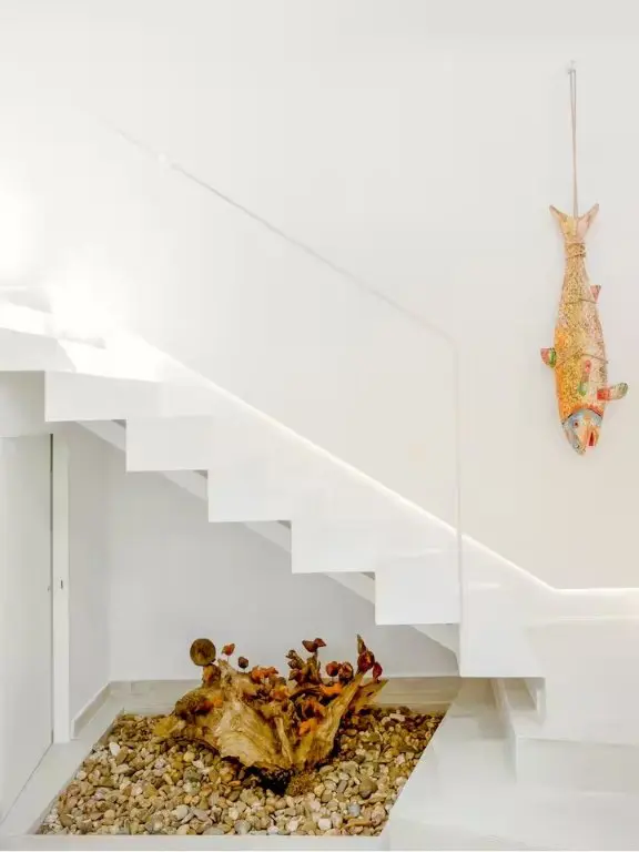 Minimal white staircase with pebble floor detail and decorative accents
