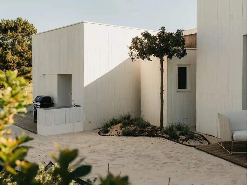 Minimal white villa exterior with sandy courtyard and coastal planting