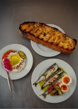 Overhead view of grilled bread, fish, and plated Mediterranean-style dishes