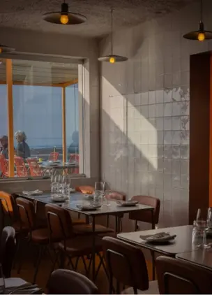 Restaurant dining room with ocean-facing windows and warm pendant lighting, Ericeira Restaurants