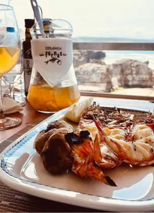 Grilled seafood platter with drinks and ocean views in the background