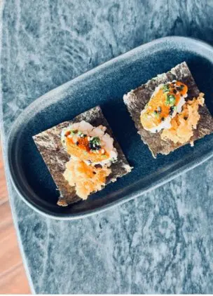 Two plated canapés served on a dark ceramic dish
