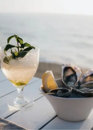 Cocktail and mussels served seaside with ocean views in the background
