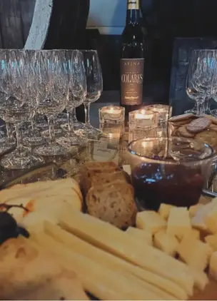 Wine tasting table with glasses, bread, cheese, and preserves in candlelight