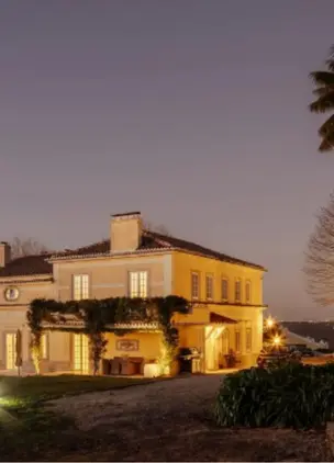 Wineries Near Lisbon Historic winery estate exterior at dusk with warm lighting and vineyard setting