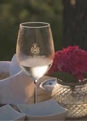 Wine glass on a dining table with floral centerpiece in an outdoor vineyard setting