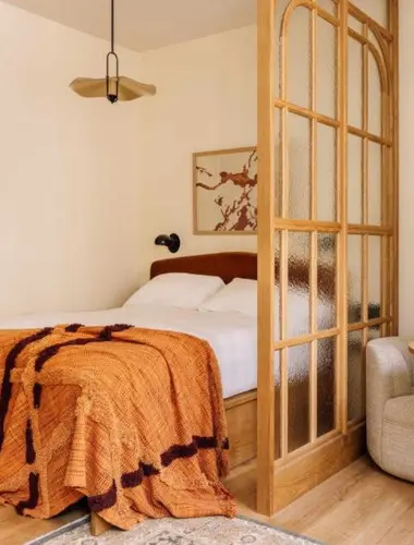 Guest room at Locke de Santa Joana Lisbon with orange linen and glazed timber door