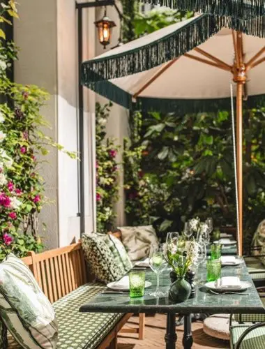 Walled garden terrace at Valverde Lisboa Hotel with green dining furniture and trailing plants