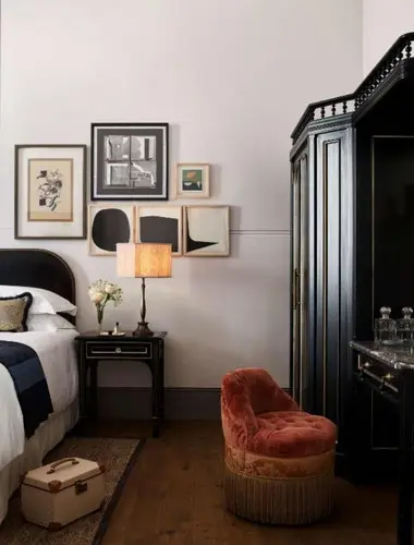 Guest room at Nomad London with gallery wall and velvet chaise longue