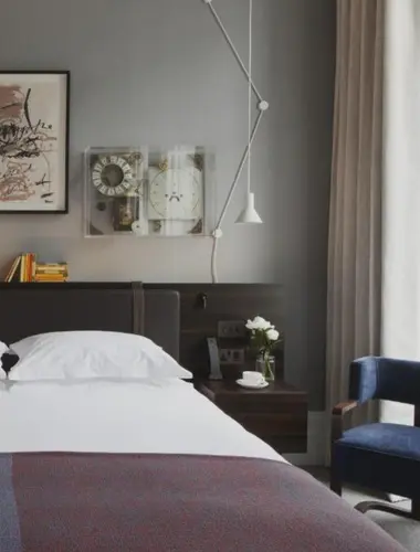 Guest room at The Laslett Notting Hill with grey walls and mid-century lamp