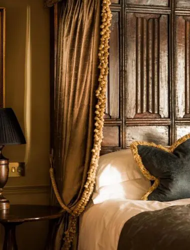 Guest bedroom at Batty Langley's London with heavy drapes and carved headboard