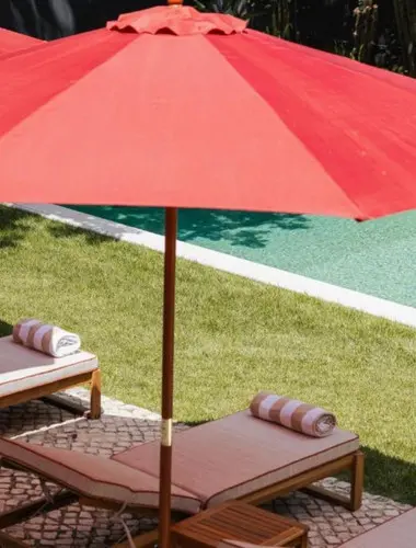 Private garden pool at Dear Lisbon Valmor Palace with red parasol and sun loungers
