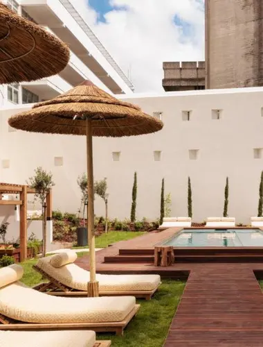 Courtyard pool at Locke de Santa Joana Lisbon with rattan umbrellas and sun loungers