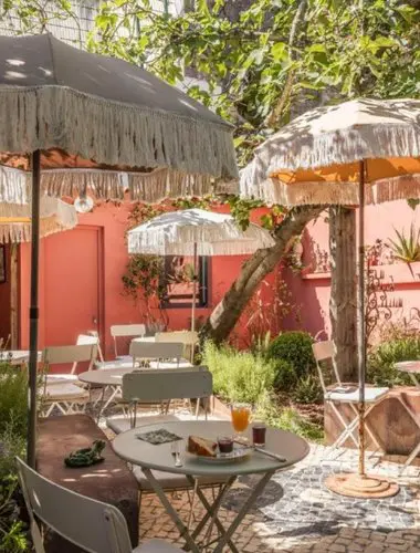 Patio garden at TocToc Lisboa with fringed umbrellas and bistro tables