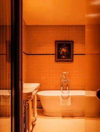 Freestanding bath at Grand Hotel Bellevue London with ochre tiled walls
