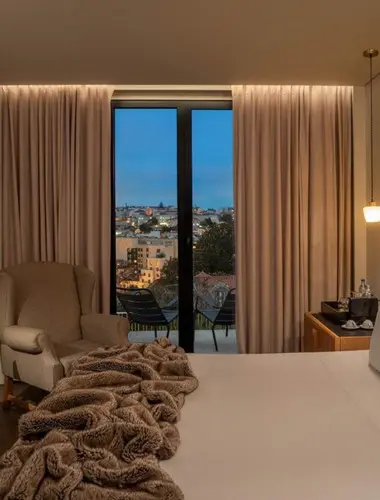 Guest room at Memmo Príncipe Real Lisbon with city views at dusk and wool throw