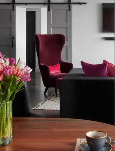 Guest room at Sea Containers London with burgundy wingback chair and dark timber furniture