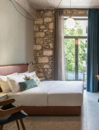 Contemporary guest room at Cohort Koukaki with exposed stone walls and local design details